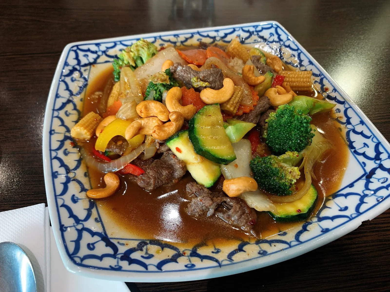 Thai cashew nut beef stir-fry with broccoli and vegetables on blue-white plate