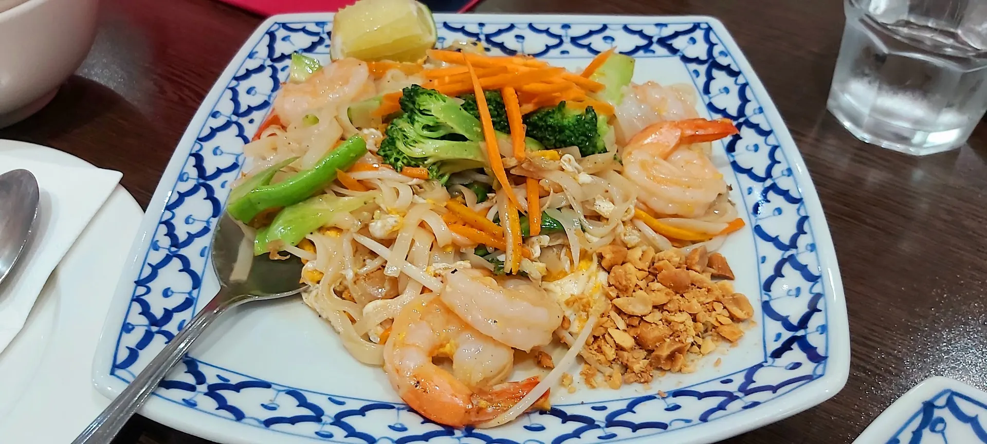 Prawn Pad Thai with rice noodles, bean sprouts and crushed peanuts on blue-white plate